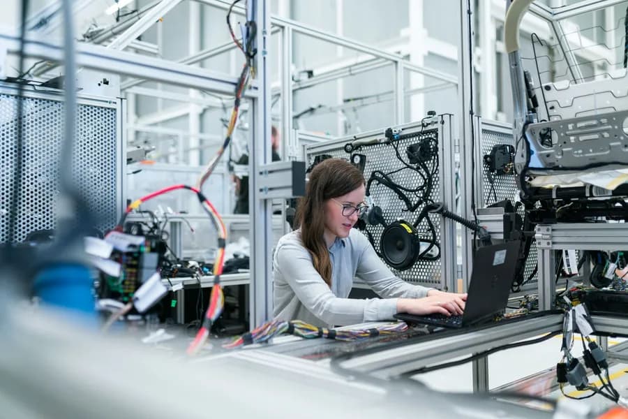 An engineer monitoring an automated production line from a laptop