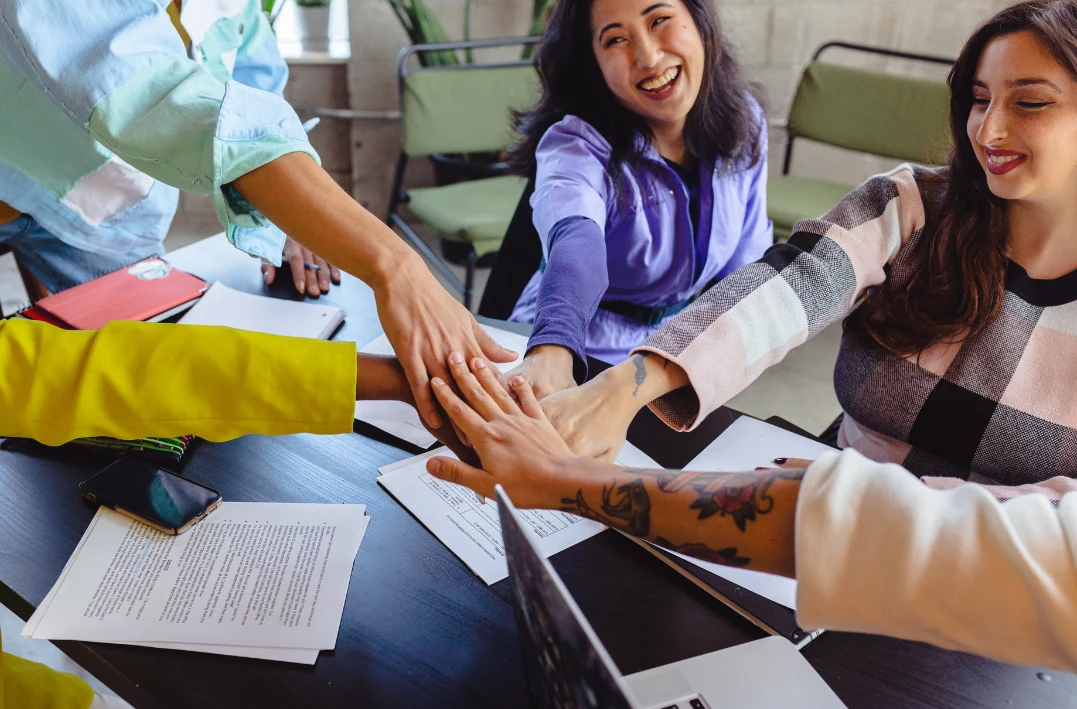 Diverse team joining hands in unity symbolizing cultural fit strategy for thriving in Indonesia’s market